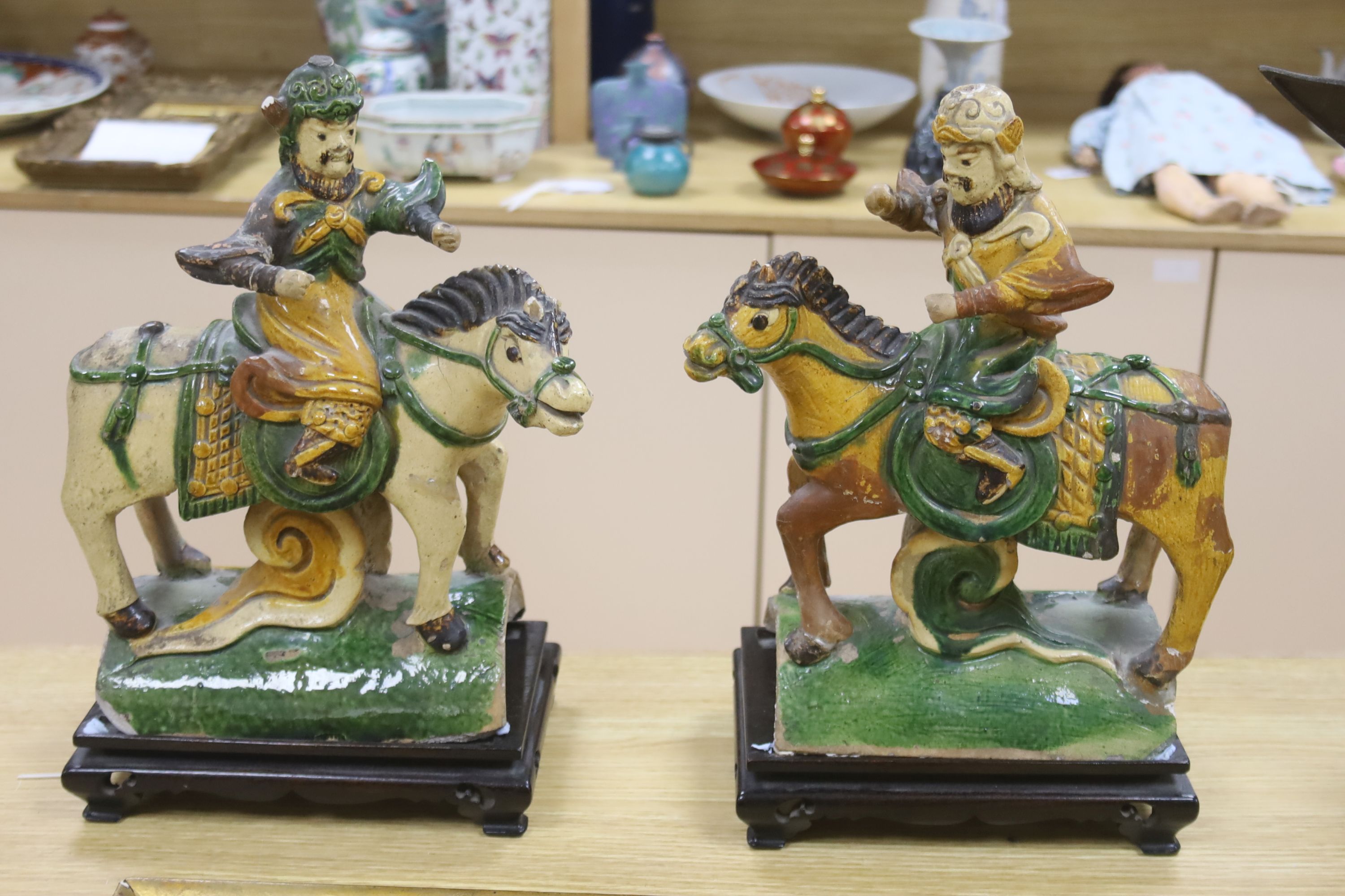 A pair of Chinese Ming sancai ‘horse and rider’ ridge tiles, height 38cm on wooden stand